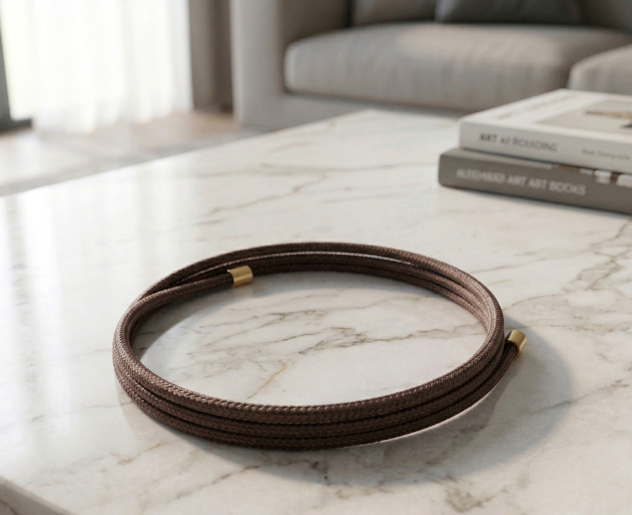 Coffee colored magnetic bracelet on a marble surface with books in the background