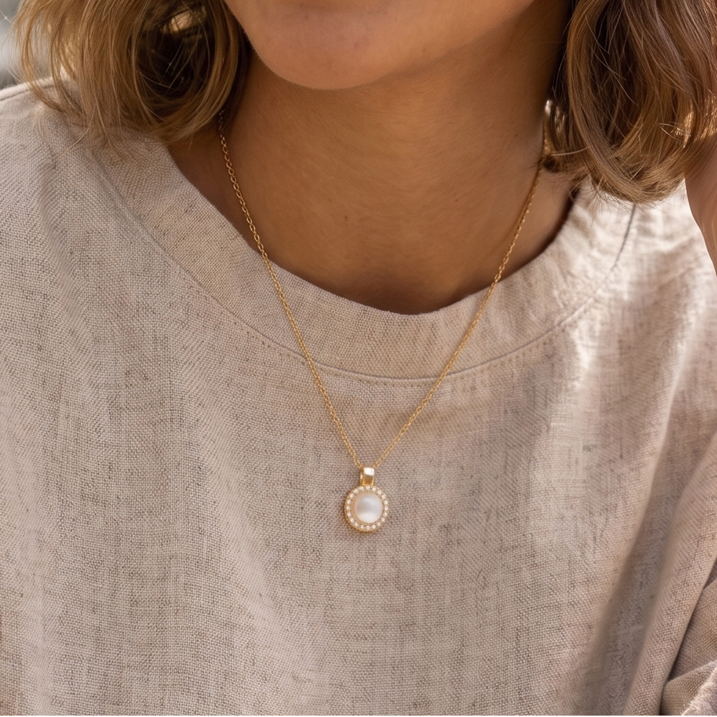 Woman wearing a light-colored shirt and a necklace with a pendant, outdoors.