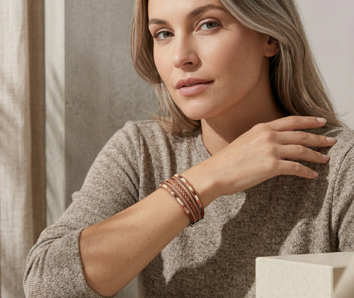 Woman wearing multiple bracelets on her wrist, sitting indoors.