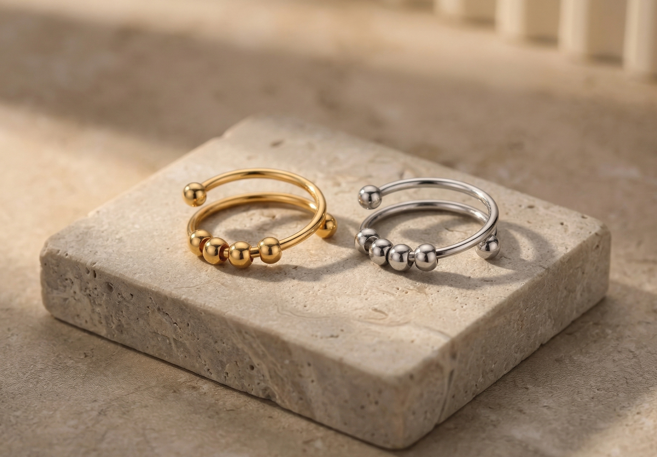 Gold and silver rings on a stone surface with a neutral background