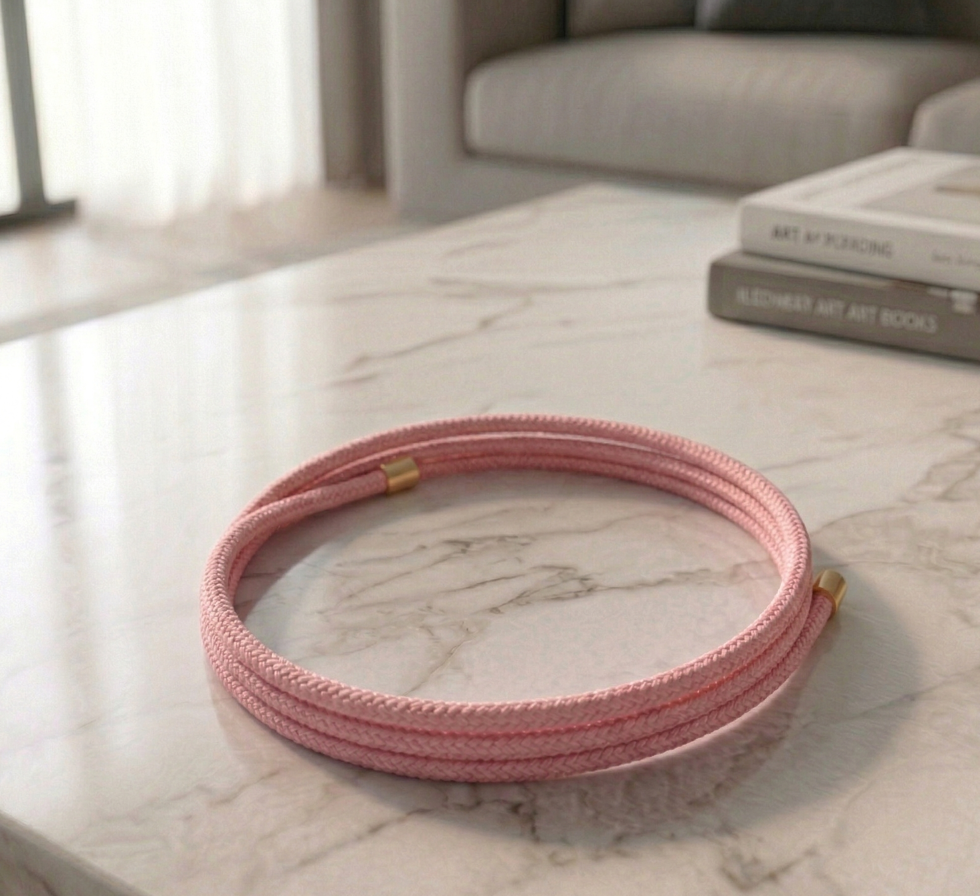 Pink magnetic bracelet on a marble surface with books in the background