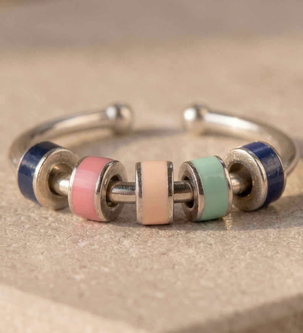 Silver ring with colorful beads on a beige background