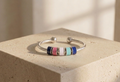 Silver bracelet with colorful beads on a beige stone surface