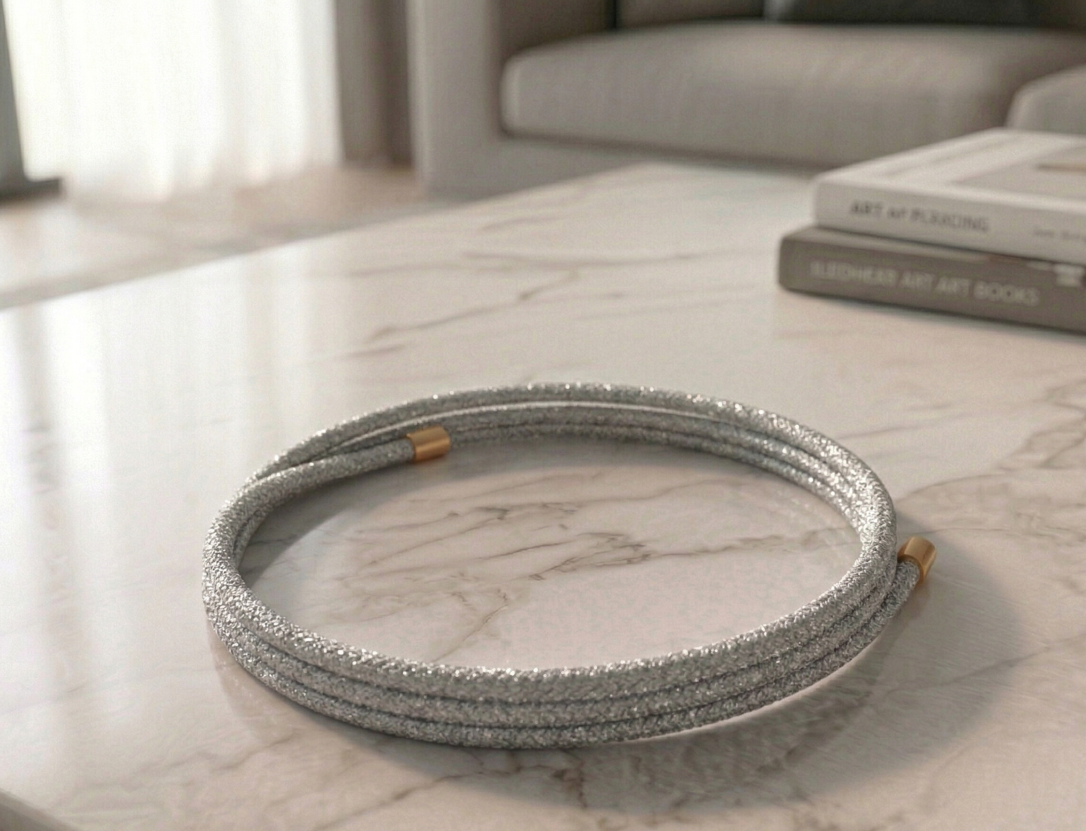 Silver magnetic bracelet on a marble surface with books in the background